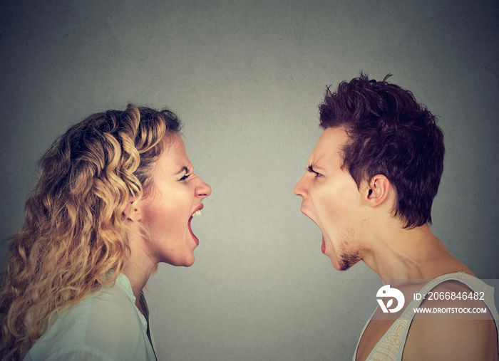 Angry young couple screaming face to face.