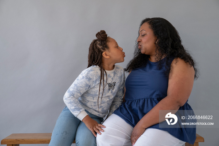 Mother and daughter (6-7) looking at each other and puckering