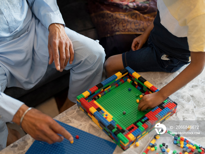 Grandfather and grandson (6-7) playing with toy blocks