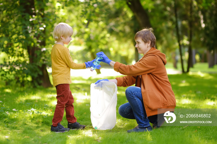 Woman volunteer and little boy picking up the plastic garbage and putting it in biodegradable trash-bag outdoors. Ecology, recycling and protection of nature. Environmental protection.