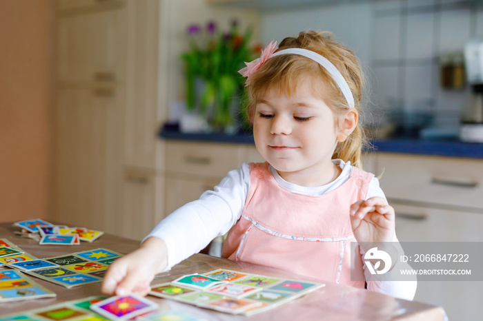 Adorable cute toddler girl playing picture card game. Happy healthy child training memory, thinking. Creative indoors leisure and education of kid during pandemic coronavirus covid quarantine disease