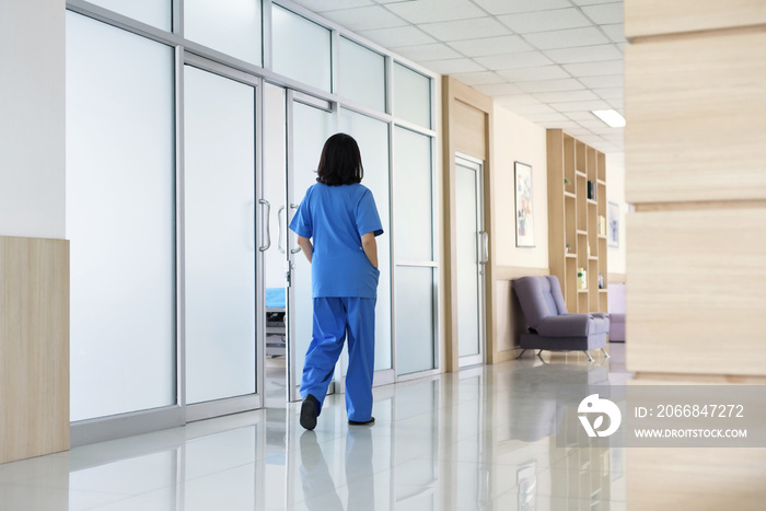 Rear view healthcare workers in scrubs walking in corridor