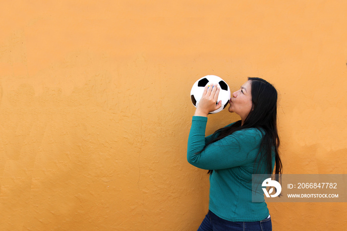 Latino adult woman plays with a soccer ball very excited that she is going to see the World Cup and wants to see her team win