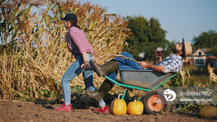 Woman takes away a wheelbarrow with a resting farmer