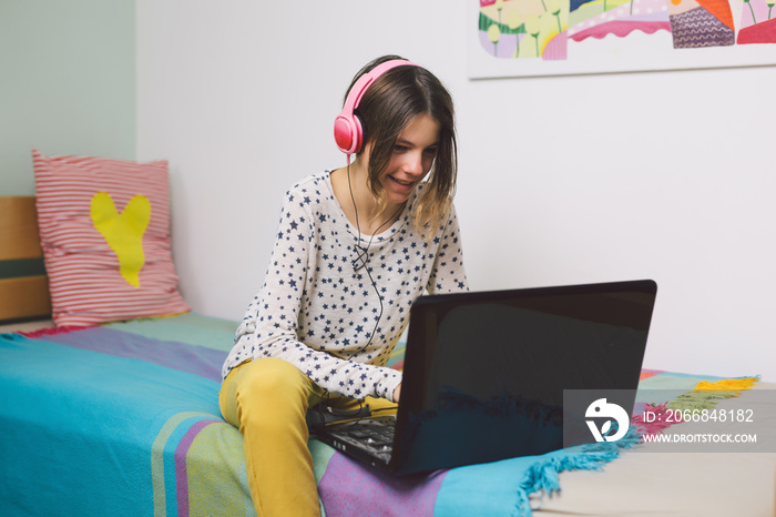 Teenage girl sitting bed and using laptop at her home