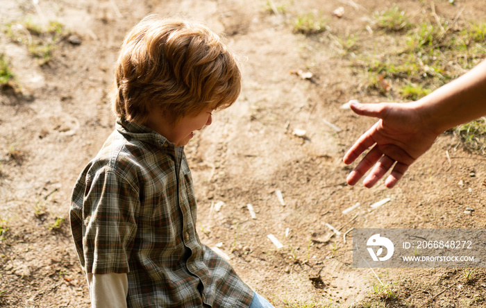 Father giving son a helping hand, hope and support children. A crying toddler sit down on the road. Kids with tears emotional. Upset child. Violence in family over children.