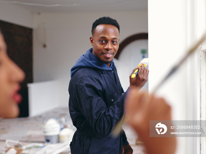 Smiling couple painting house walls