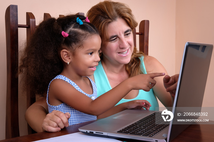 Multiracial small girl and her mother using a laptop computer at