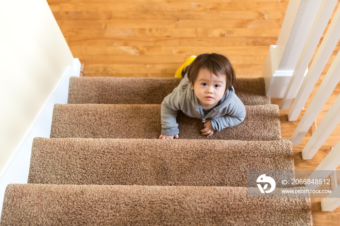 Toddler boy climbing a staircase in his house