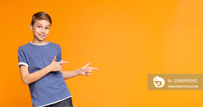 Cute little boy pointing away on orange background