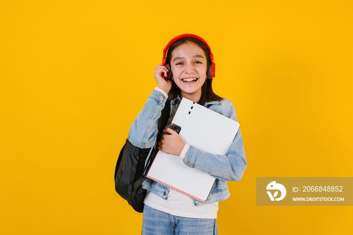 portrait of young hispanic child teen girl student with headphones listening music on a yellow background in Mexico Latin America