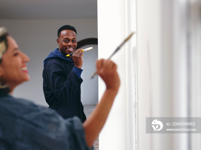 Smiling couple painting house walls