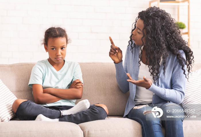 Angry black mom scolding naughty little daughter at home