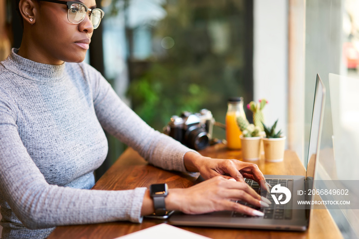 Crop female entrepreneur browsing laptop