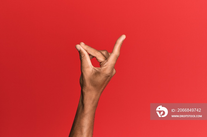 Hand of hispanic man over red isolated background snapping fingers for success, easy and click symbol gesture with hand