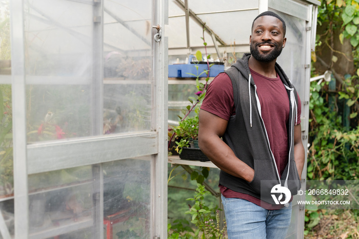 Portrait of smiling man standing in front of greenhouse