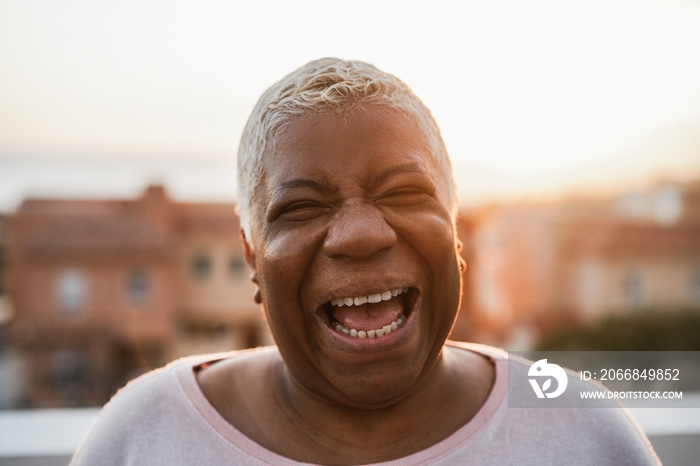 Happy senior african woman smiling on camera outdoor in the city - Focus on face