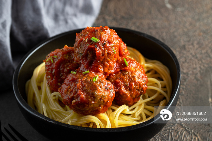 Close up of beef meatball in tomato sauce served with spaghetti