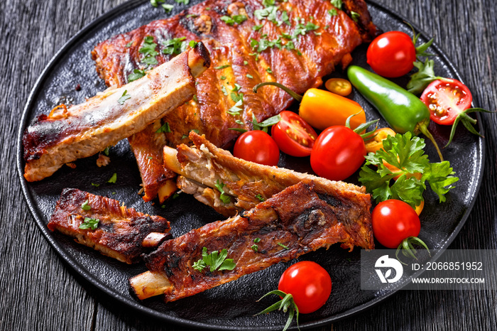 BBQ Ribs with tomatoes and chili on  black plate