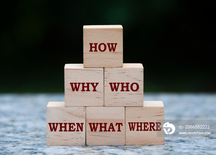 Text on wooden blocks with blurred nature background - How, Why, What, When, Where, Who.