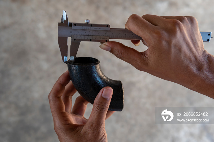 Using Vernier caliper to measure the dimensions thickness of the Elbow Pipe Fittings.