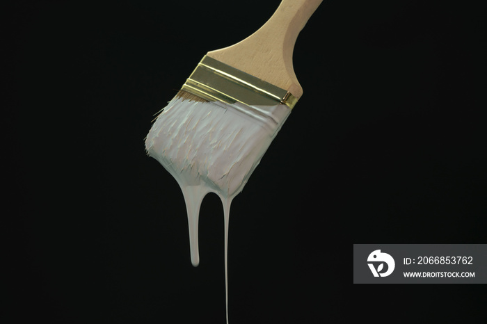 Dripping white paint brush on a blackbackground.