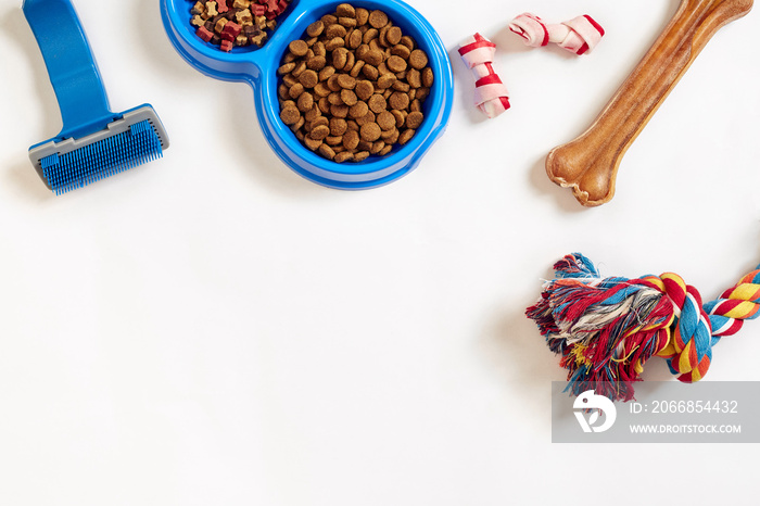 Dog care items, isolated on white background. Dry pet food in bowl, toy and bones. Top view