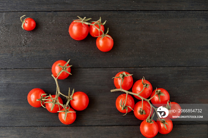 Three branches of red cherry tomatoes isolated on black wooden background. Top view