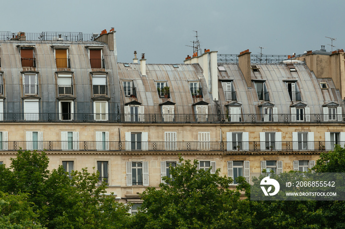 Typical old Paris architecture, facades of residential buildings with roofs, chimneys and mansards, expensive real estate concept. City residents self isolation, european lifestyle