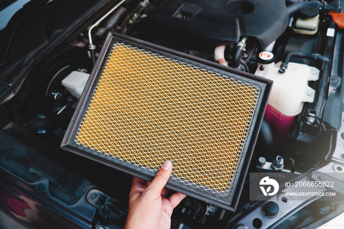 A auto mechanic carries a replacement car air filter for car engine maintenance