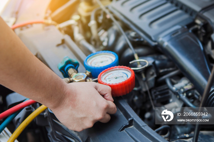 Auto mechanic  Worker hands  holding  monitor to check and fixed car air conditioner system in  car garage