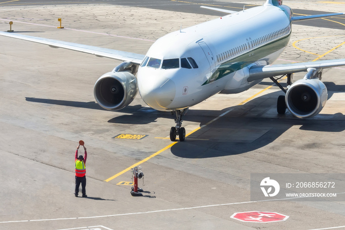 Ground staff airplane marshaller meets passenger plane after landing flight.