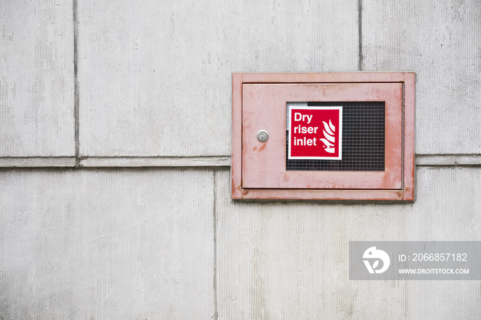 Dry riser inlet box red on brick wall for emergency fire services water connection for hose brigade engine at shopping mall retail park