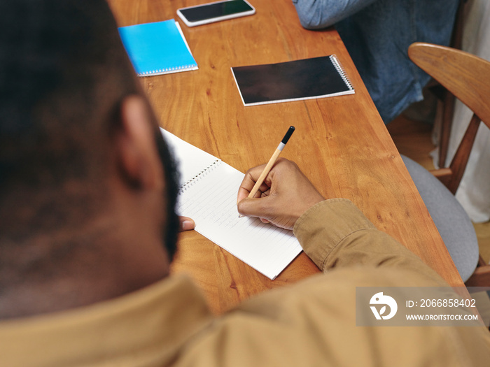 Close-up of man writing in notepad