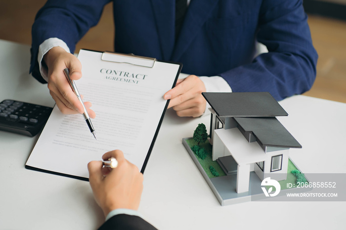 hand of young man customer signing contract for buying house with real estate broker in suit at estate agent office, investment, home loan contract, buying house, real estate and insurance concept