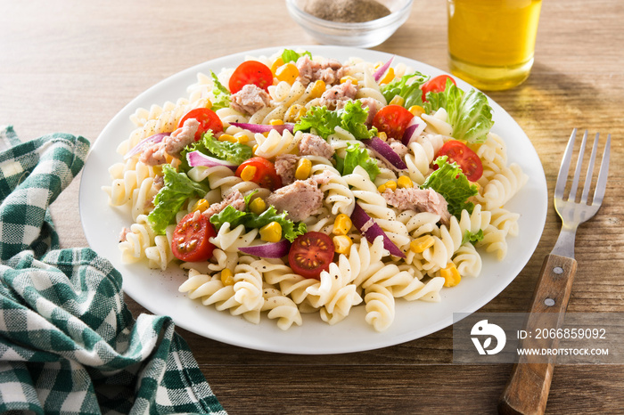 Pasta salad with vegetables and tuna on wooden table