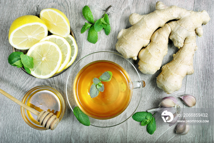 Honey, ginger, lemon, garlic and a cup of tea on a wooden table. for cold and flu. top view.