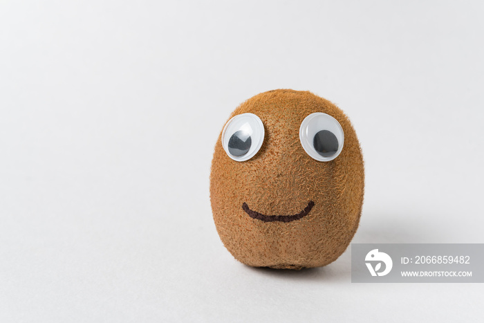 Funny kiwi fruit with Googly eyes and smile on white background. Kiwi character