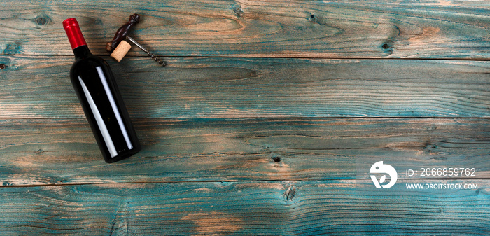 Red wine background with bottle and corkscrew on faded blue wood