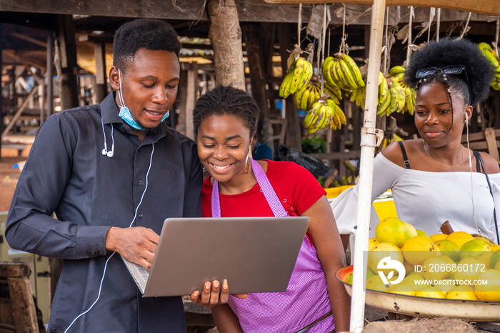 young business man talking with a woman in a market showing her something on his laptop