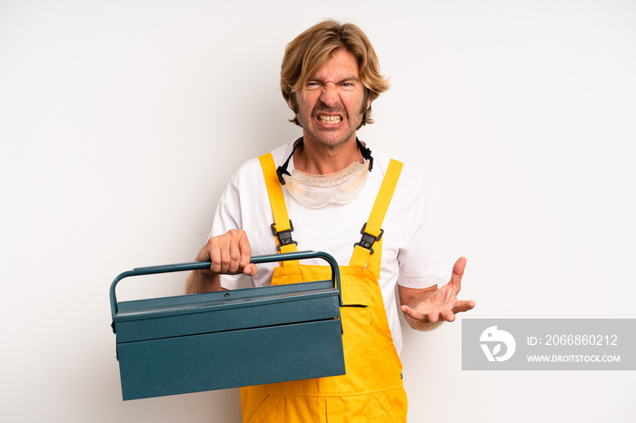 adult blond man looking angry, annoyed and frustrated. repairman with a toolbox concept