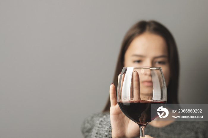 abstinence alcohol, stop liquor, teenager shows a sign of rejection of wine with her hand, refusal of alcoholism of minors