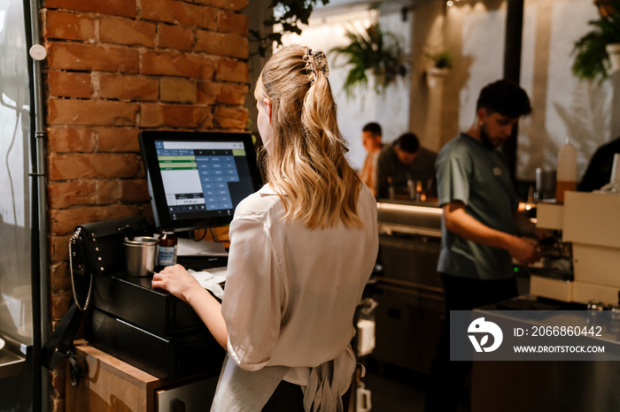 Young woman holding order receipts while working in restaurant kitchen