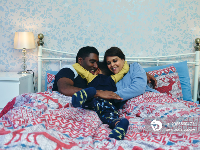 Boy hugging parents in bed