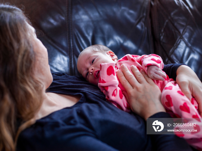 Mother lying on sofa with infant daughter