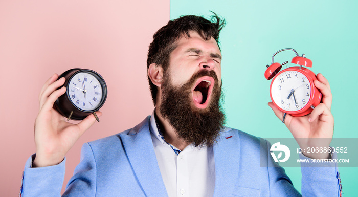 Guy unshaven puzzled face having problems with changing time. Time zone. Changing time zones affect health. Does changing clock mess with your health. Man bearded hipster hold two different clocks