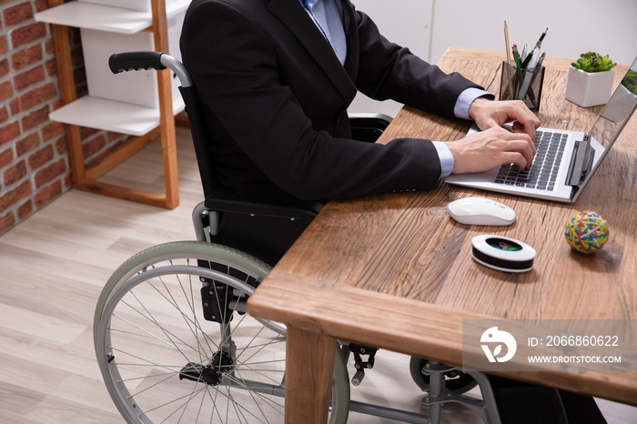 Businessman Sitting On Wheelchair Using Laptop