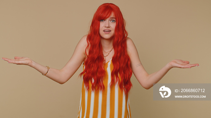 What Why. Sincere irritated redhead woman raising hands in indignant expression asking reason of failure demonstrating disbelief irritation by troubles. Confused girl isolated on beige wall background