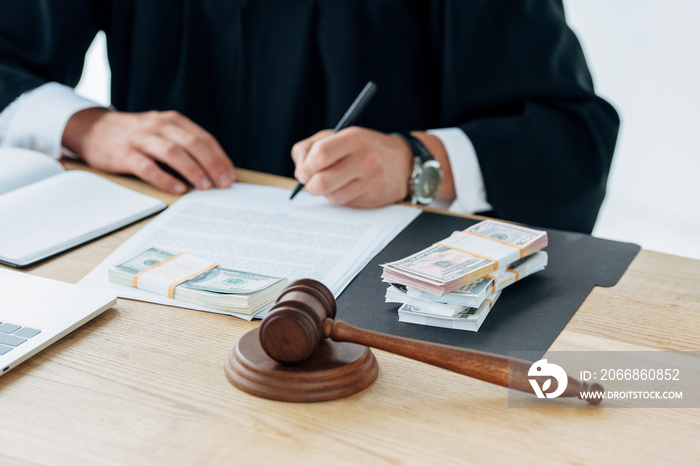 panoramic shot of wooden gavel near judge writing near money in office