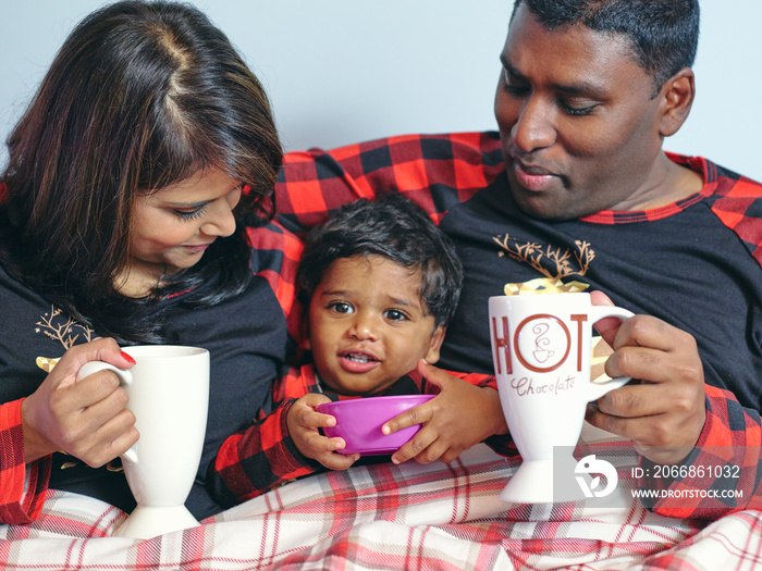 Parents with son drinking and eating in bed